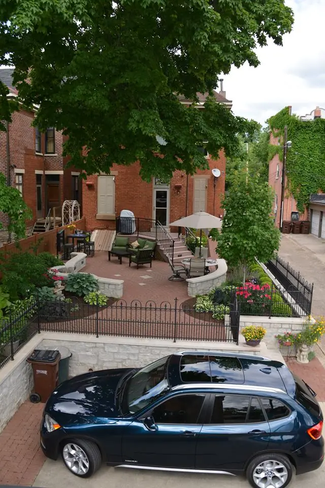 An aerial view of a brick courtyard patio by Perrino Landscape lit by string lighting after dark