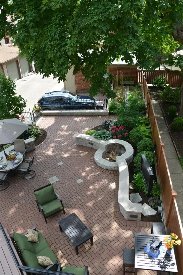 Aerial view of a completed Perrino Landscape project: a herringbone brick paver terrace with a curved limestone seat wall, fire feature and planted beds