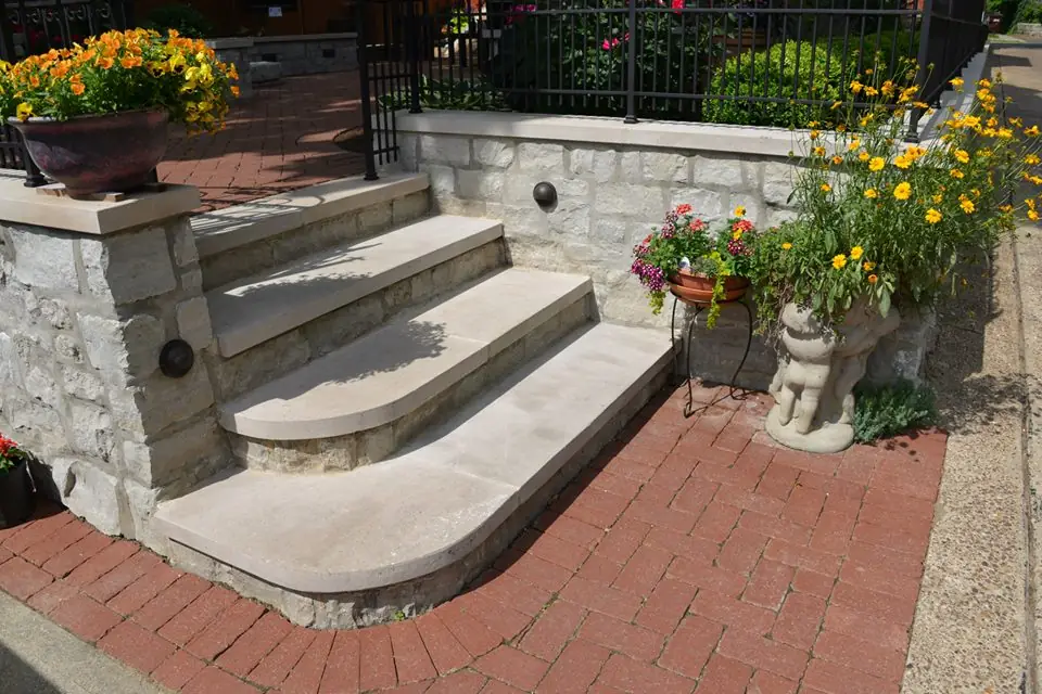 Stone entry steps and a retaining wall planted with potted flowers at a Cincinnati home