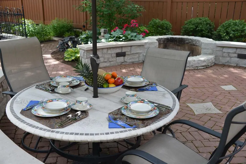 The finished terrace on a Perrino Landscape patio project in Mt. Lookout, dining furniture set out under the trees