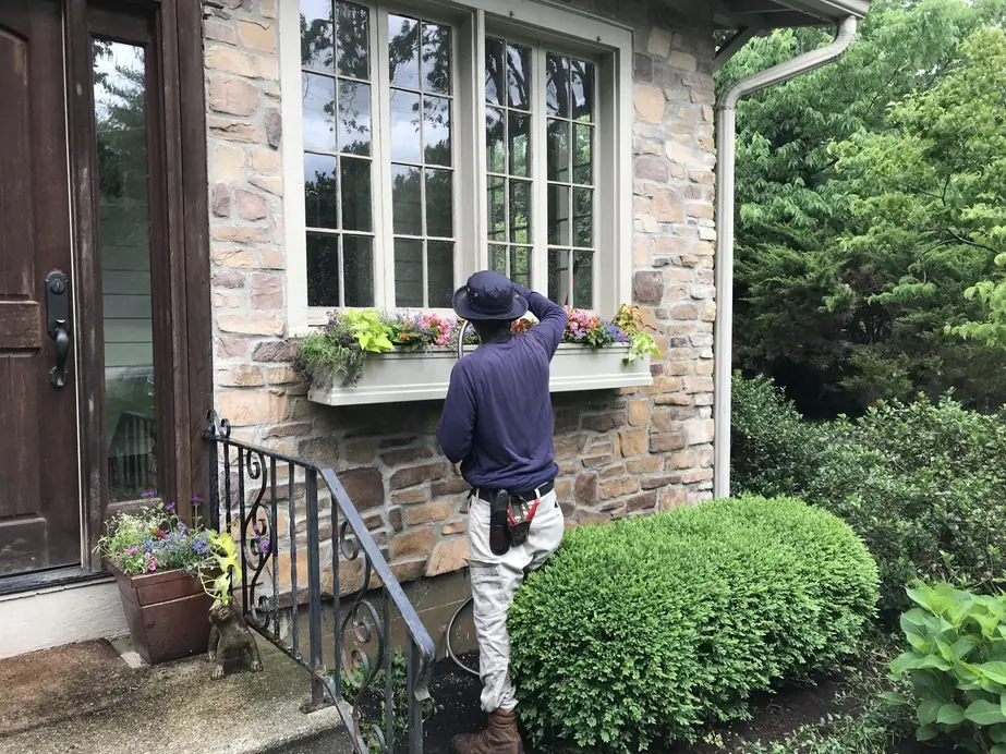 A Perrino Landscape crew member tending a window flower box at a stone Cincinnati home