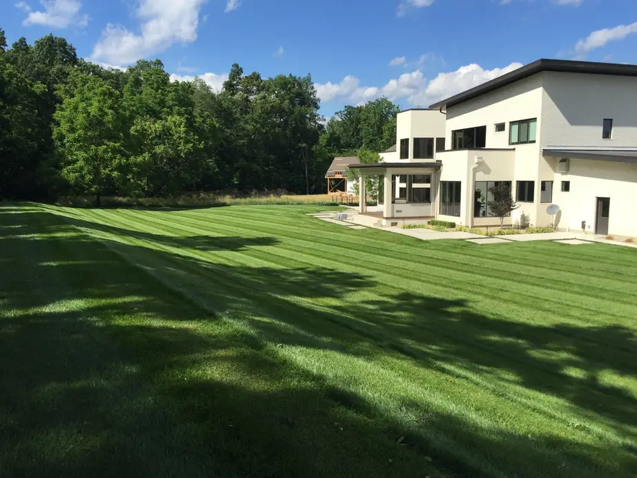 A striped estate lawn maintained by Perrino Landscape running back to the house
